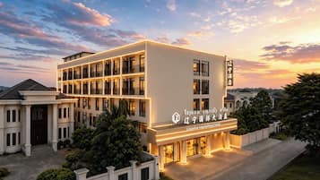 Ein mehrstöckiges Hotel mit moderner Fassade, beleuchteter Beschilderung und einer gepflegten Außenanlage.