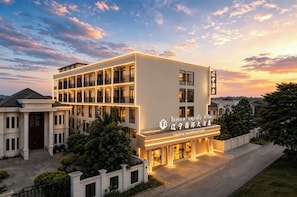 A multi-story hotel with a modern facade, illuminated signage, and a well-maintained surrounding landscape.