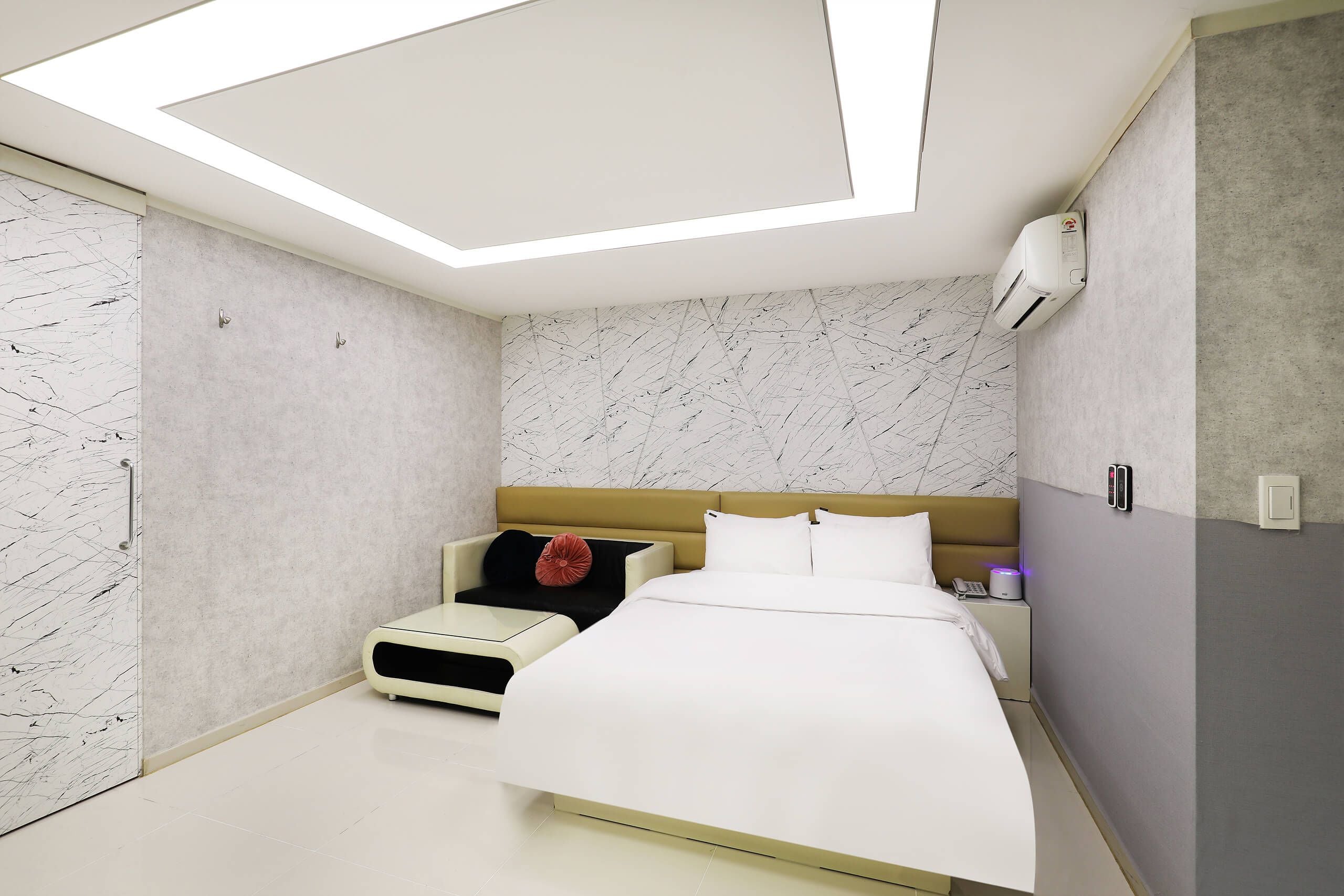A modern bedroom with a bed, bedside table, and a small seating area.