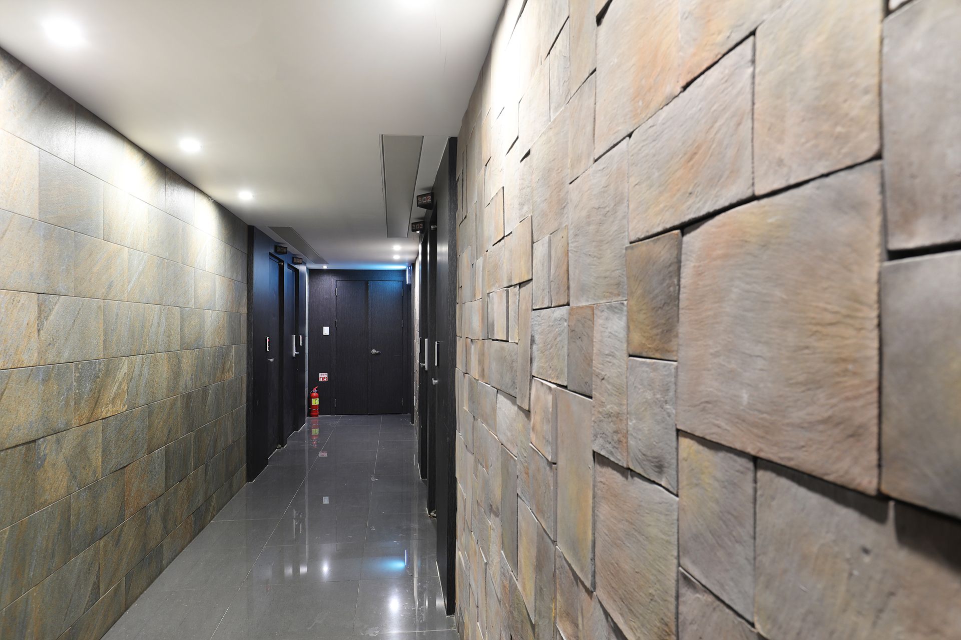 A corridor with tiled walls and a fire extinguisher.