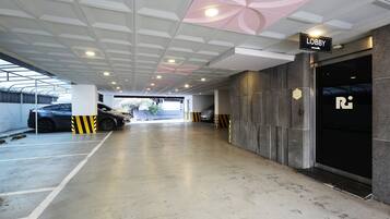 A parking garage with a 'Lobby' sign, a car parked by the wall, and a building entrance with a 'R' logo.