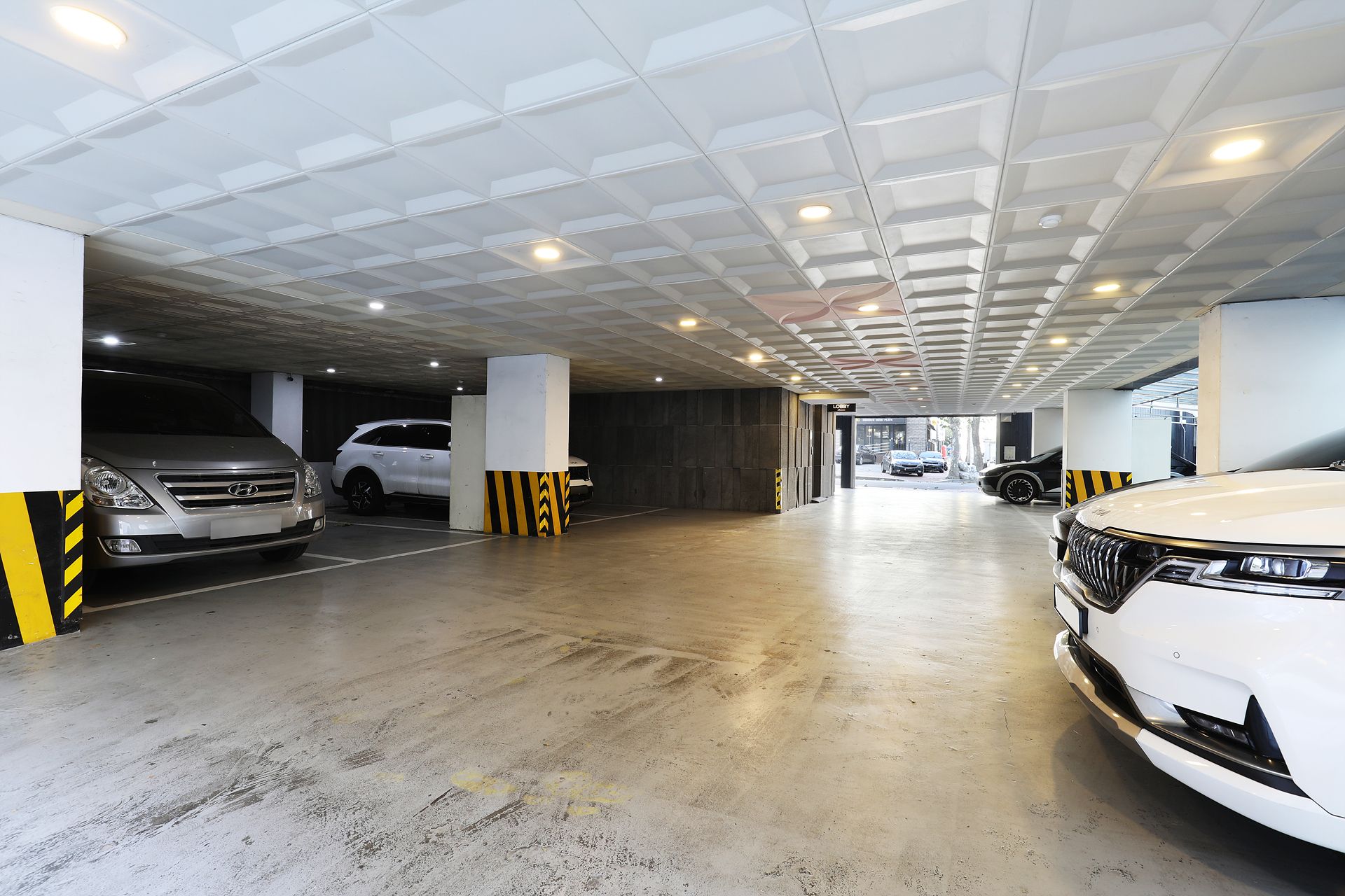 A parking garage with multiple levels, concrete floors, and a modern ceiling design.