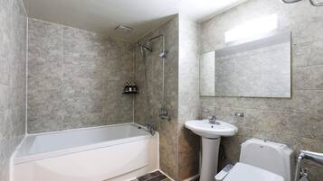 Een moderne badkamer met een bad, een wastafel en een toilet.