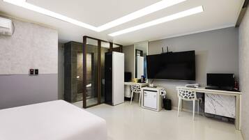 Une chambre d’hôtel moderne équipée d’un lit, d’un bureau, d’une télévision et d’un mini-bar.