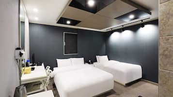A hotel room with two beds, a desk with a computer, a hairdryer, and a mirror.