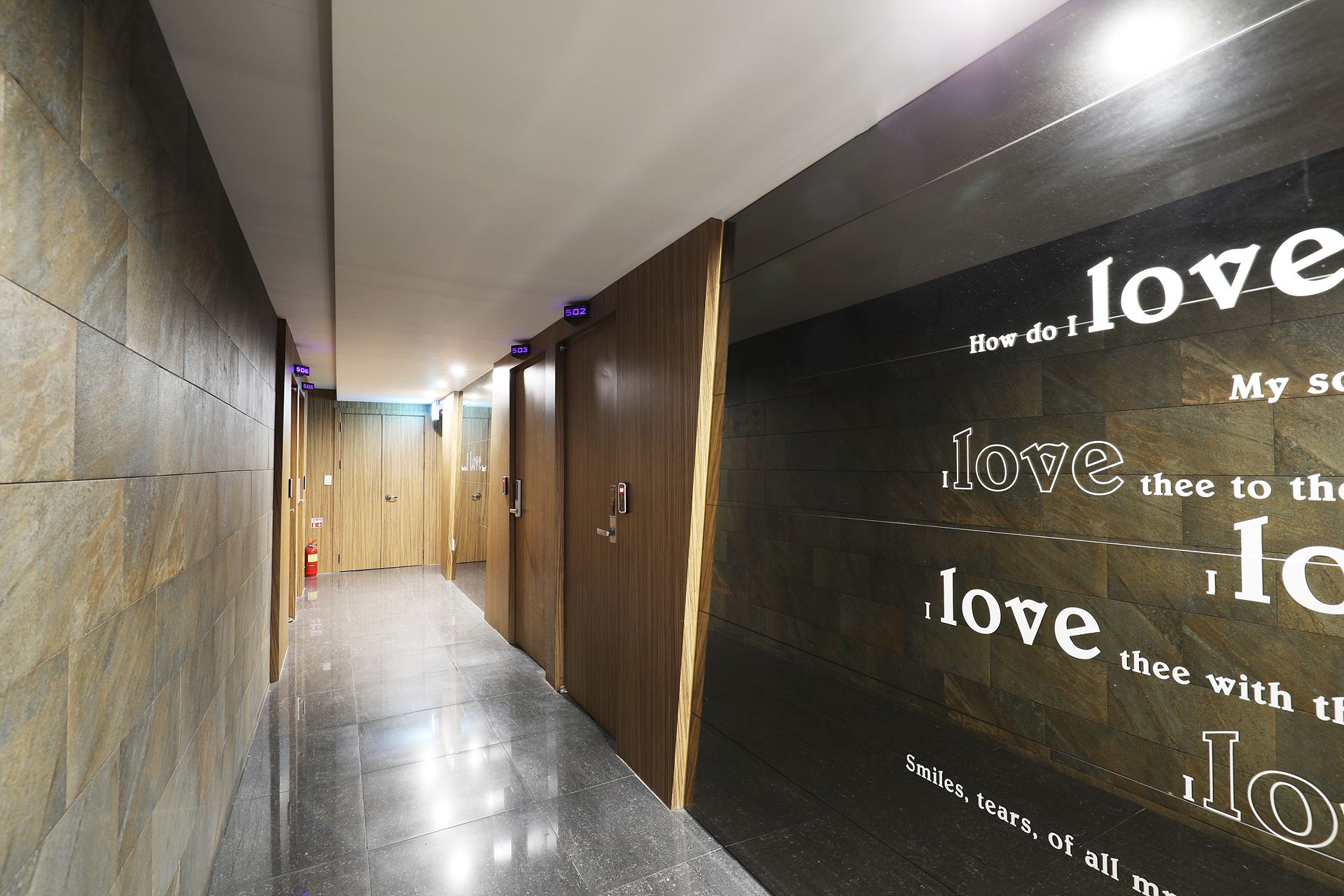 A hallway with a reflective floor, wooden doors, and a wall with a motivational quote.