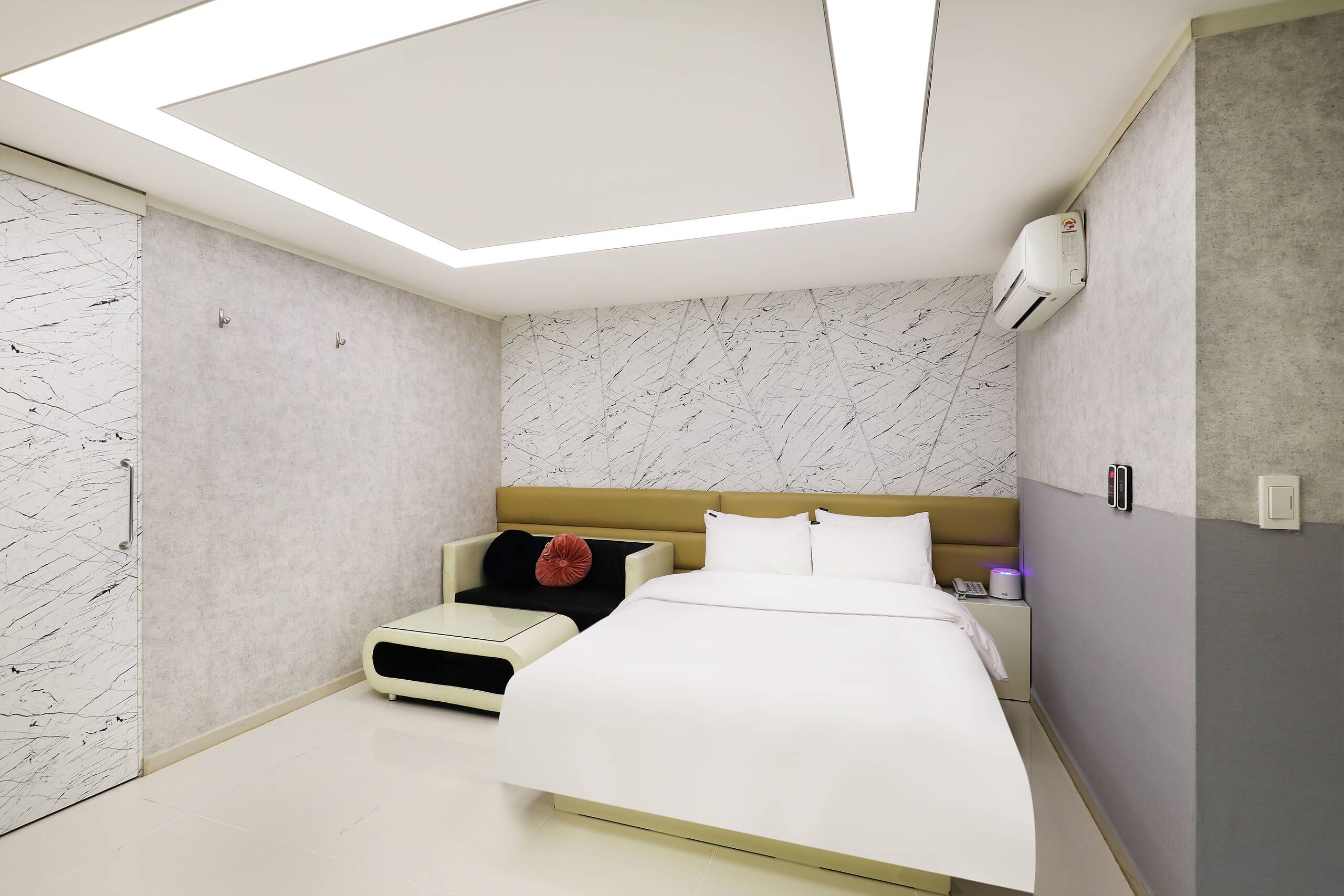 A modern bedroom with a bed, bedside table, and a small seating area.
