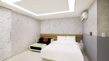 A modern bedroom with a bed, bedside table, and a small seating area.