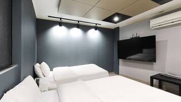 A modern bedroom with a large bed, a flat-screen TV mounted on the wall, and a ceiling-mounted light fixture.