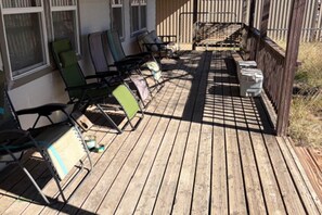 Una terraza de madera con mobiliario exterior, incluyendo sillas y una mesa.