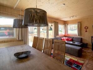 A wooden interior with a dining table, chairs, a sofa, and a hanging light fixture. - One-bedroom Cabin (Sankt Georgen am Kreischberg)