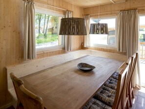 A wooden interior with a large dining table, cushioned bench seating, and a hanging light fixture. - One-bedroom Cabin (Sankt Georgen am Kreischberg)
