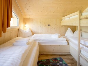 A cabin with two bunk beds, a window with curtains, and a wall-mounted light. - One-bedroom Cabin (Sankt Georgen am Kreischberg)