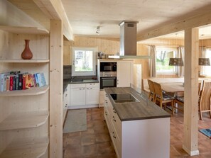 Eine kompakte Küche mit weißen Schränken, einer zentralen Kochinsel und einem Essbereich mit Holzmöbeln.