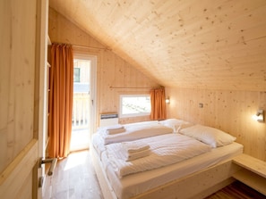 A room with a wooden ceiling, a bed with white linens, a window with curtains, and a small bedside table. - One-bedroom Cabin (Sankt Georgen am Kreischberg)