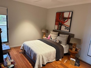 A bedroom with a bed, bedside lamps, a painting, and a window. - Hilltop Getaway (Ocean View)