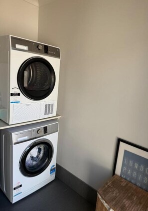 A stacked washer and dryer unit in a room with a framed picture on the wall. - Hilltop Getaway (Ocean View)