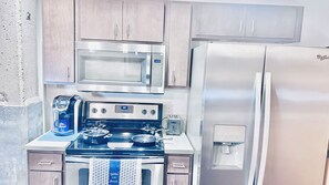 A compact kitchen with a microwave, refrigerator, stove, and a coffee maker. - Studio in the Heart of
DSM Downtown (Des Moines)