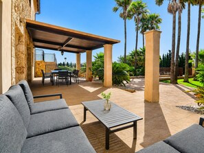 An outdoor patio with a covered seating area, a table, and a potted plant. - Cabin in Muro With Swimming Pool (Muro)