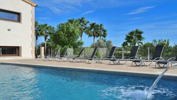 A swimming pool with lounge chairs and palm trees in the background.