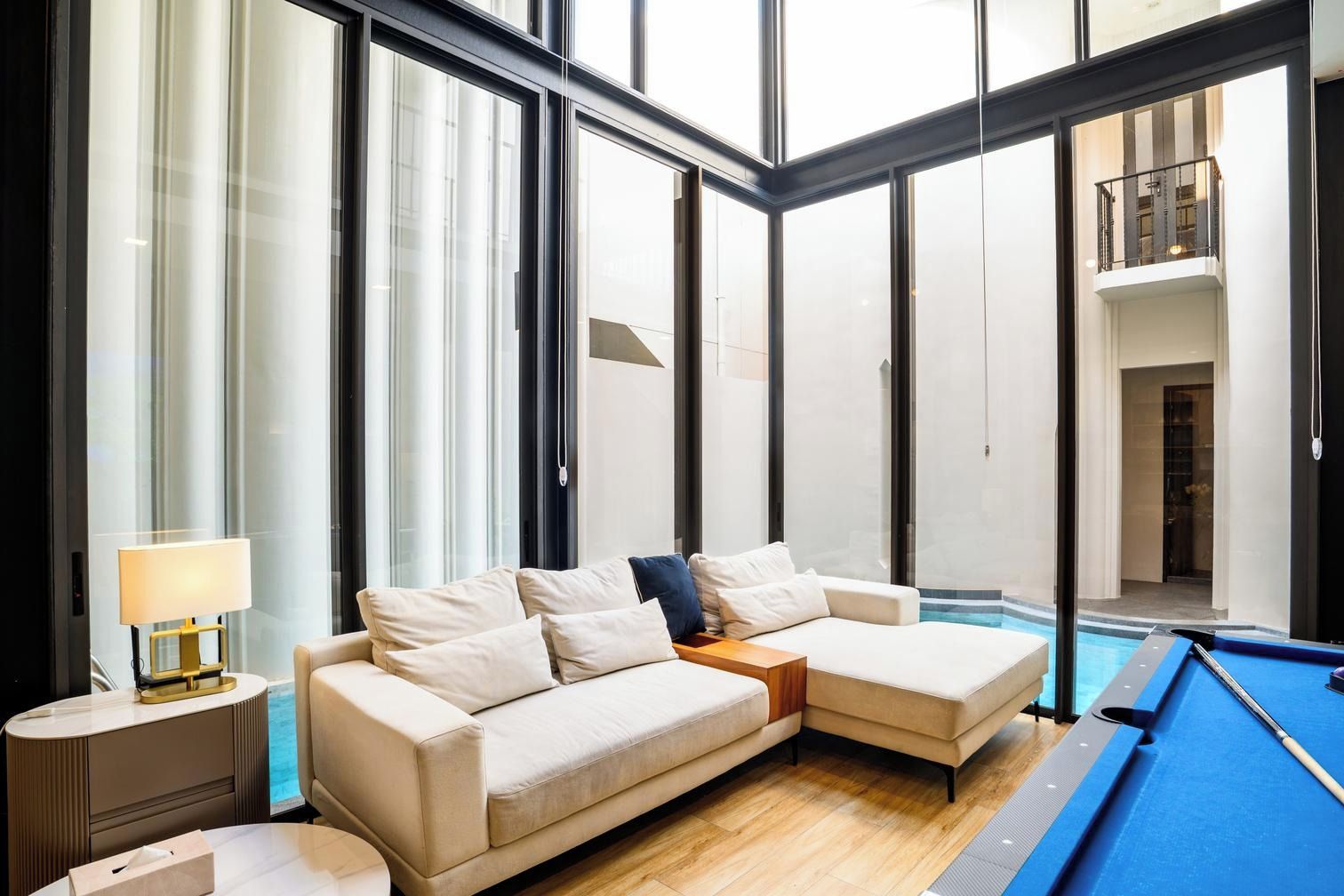 A modern living room with a sofa, a pool table, and a lamp.