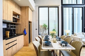 A modern kitchen with wooden cabinets, a built-in oven, and a dining area with a table set for six. - Modern 4BR Pool Villa Good Location(PI4) (Pattaya)