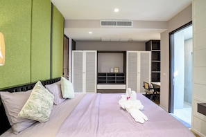 A hotel room with a bed, a desk, and a sliding closet door. - Modern 4BR Pool Villa Good Location(PI4) (Pattaya)