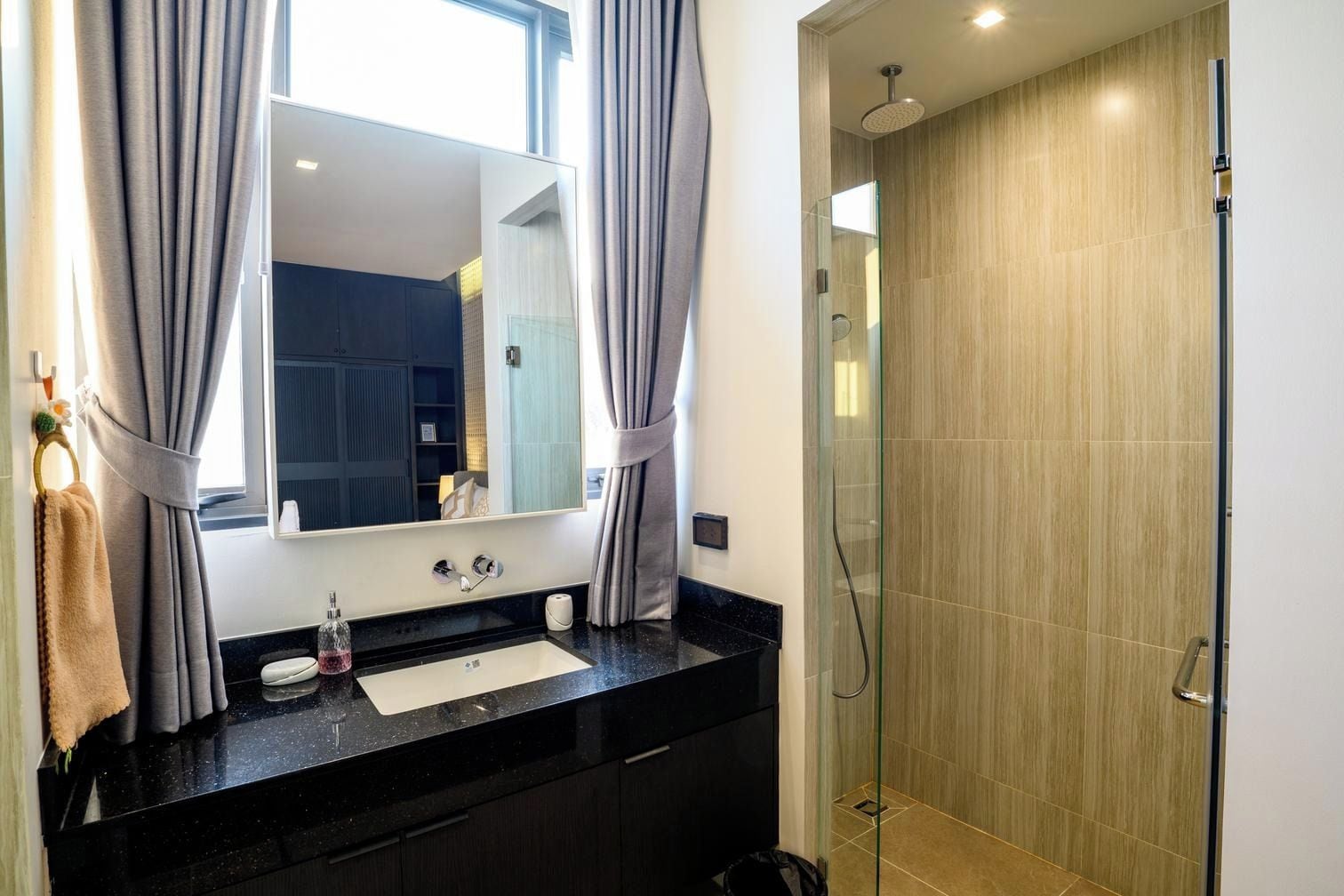 A modern bathroom with a black countertop, a mirror, and a glass-enclosed shower.