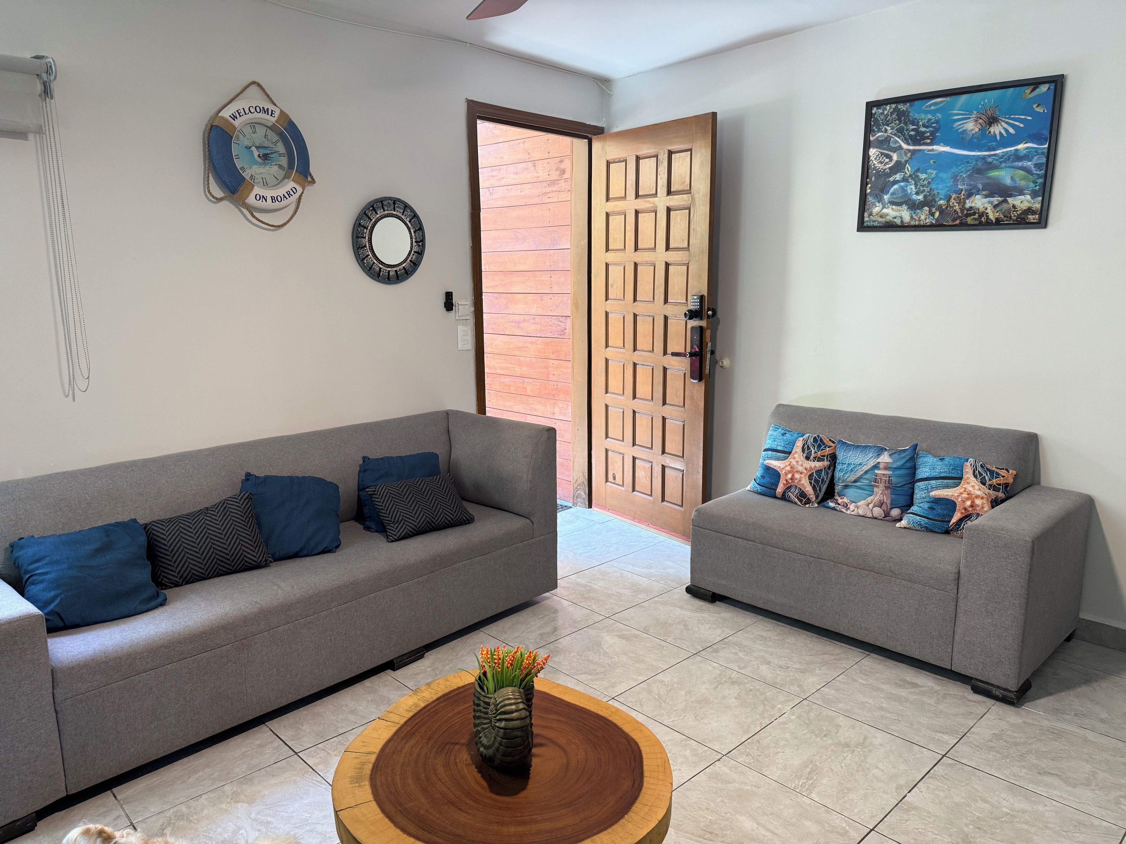 A living room with two grey sofas, a wooden coffee table, and a wall clock.