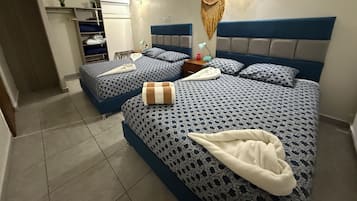 Ein Hotelzimmer mit zwei Betten, einem Schrank, einem Nachttisch und einer Wand-Klimaanlage.