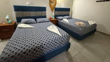 Een hotelkamer met twee bedden, elk met een geborduurde spreideken, een bedlampje en een decoratief object aan de muur.