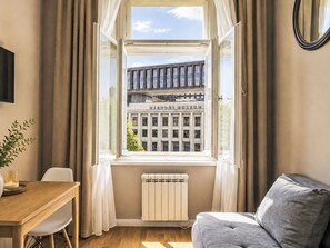 A room with a window, a radiator, a table with a plant, and a sofa. - Washington by Interhome (Prague centre)