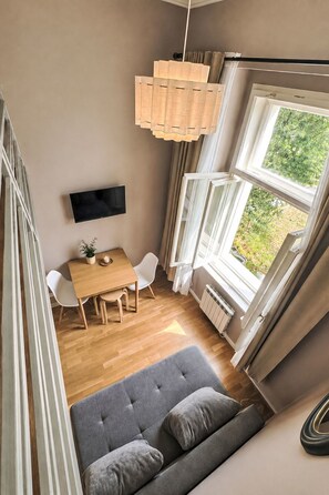 A room with a dining table, chairs, a sofa, a TV, and a window with curtains. - Washington by Interhome (Prague centre)