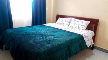 Una cama individual con cabecera de madera en una habitación con suelo de baldosas.
