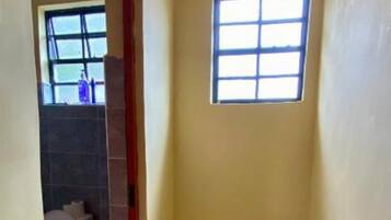 Un baño con inodoro, ventana y piso de baldosas.