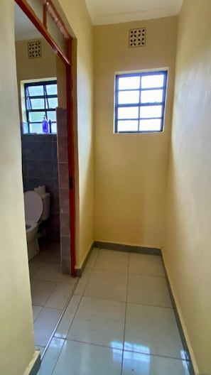 Une salle de bain avec des toilettes, une fenêtre et un sol carrelé.