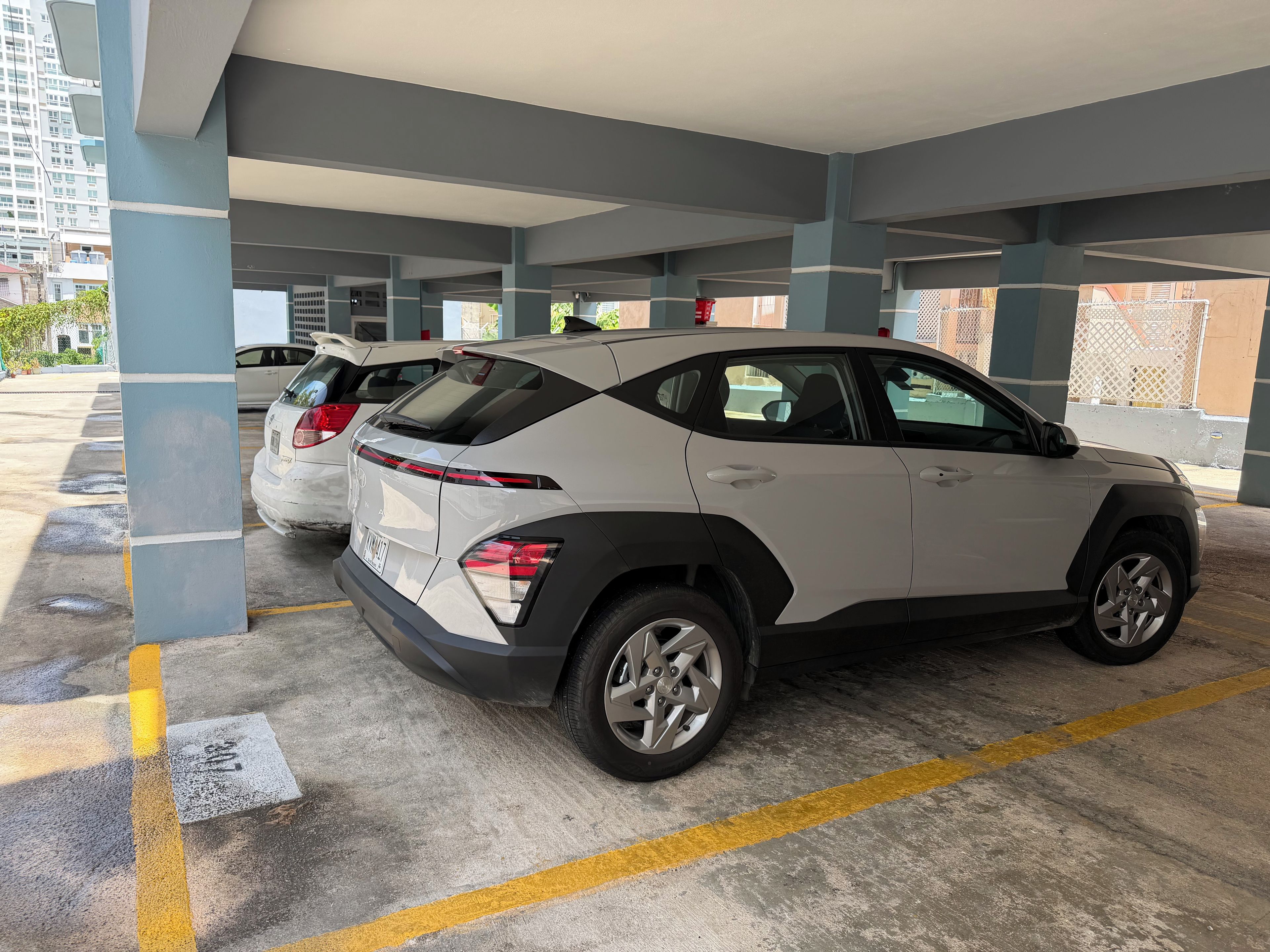 Un parking avec des piliers en béton, des emplacements de stationnement délimités et un VUS blanc garé dans l’un de ces emplacements.