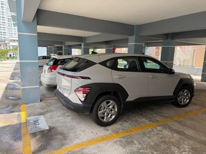 Ett parkeringsgarage med betongpelare, markerade parkeringsplatser och en vit SUV parkerad på en av platserna.