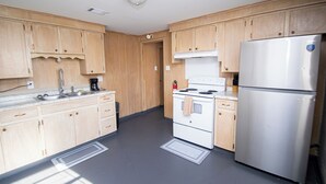 Une cuisine avec des meubles de rangement en bois, un réfrigérateur en acier inoxydable, une cuisinière et un évier.