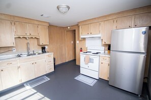 Eine Küche mit Holzausstattung, einem Edelstahlkühlschrank, einem Herd und einem Spülbecken.
