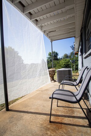 Une terrasse extérieure dotée d’un espace abrité, d’une table et de deux chaises.