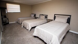 Une chambre avec trois lits simples, une petite table et une chaise.