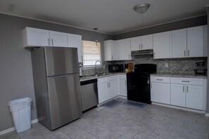 A kitchen with white cabinets, stainless steel appliances, and a granite countertop.
