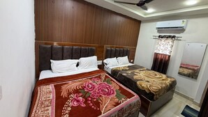 A hotel room with two beds, a ceiling fan, an air conditioning unit, and a mirror on the wall. - Om Home Stay (Mayapura)