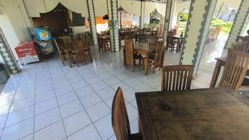 Un restaurant avec un sol carrelé, des tables et des chaises en bois, et une vue sur l’extérieur.