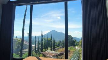 Quarto com uma janela grande, uma cama e vista para uma montanha.