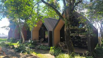 A modern building with a covered outdoor seating area surrounded by lush greenery.