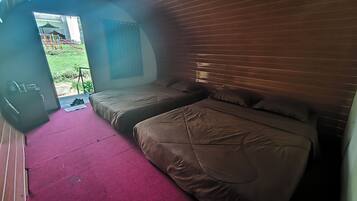 A room with two beds, a red carpet, a wooden headboard, and a view of a playground outside.