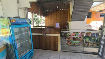 A small shop with a blue refrigerator, a wooden counter, and a snack display.