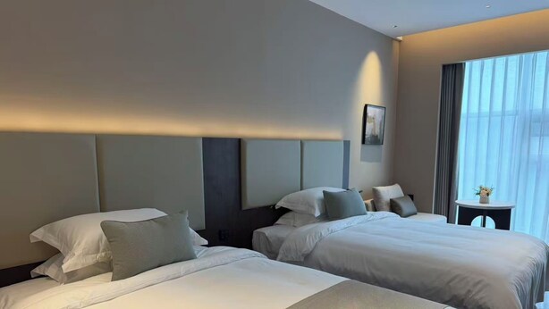 A hotel room with two beds, a small table, and a window with curtains. - WUHAN BOLEST HOTEL (Wuhan)
